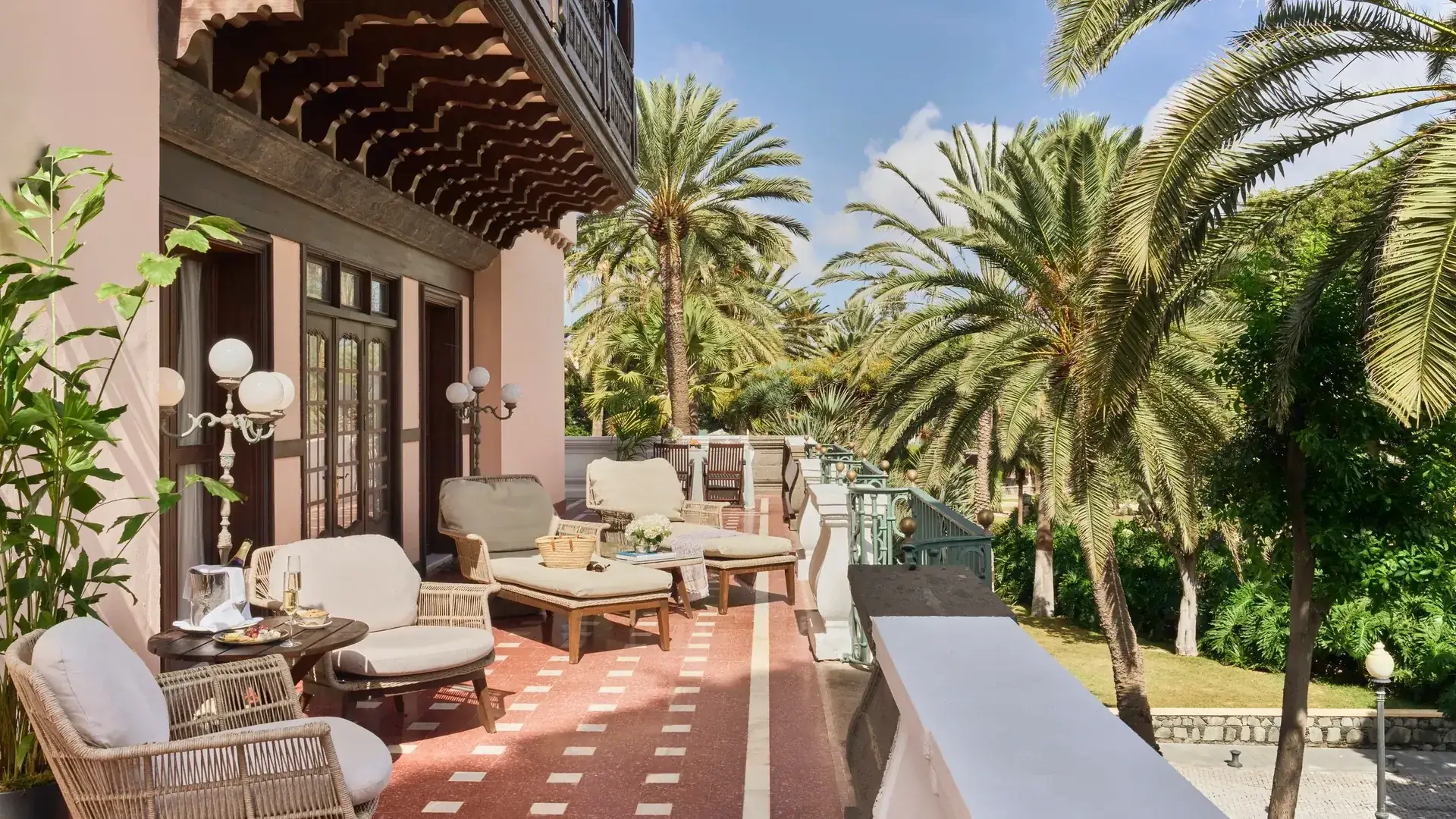 Terraza con sillones y tumbonas entre palmeras en un alojamiento con carácter